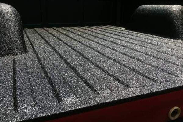 Close-up of a pickup truck bed with a textured Rhino Liner coating, showcasing durable, non-slip protection.